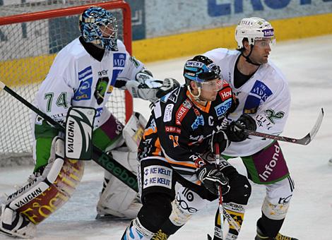 Philipp Lukas Liwest Black Wings Linz im Duell mit Greg Kuznik vor dem Tor der Laibacher gehuetet von Norm Miracle.